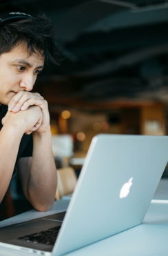 man wearing headphones while sitting on chair in front of MacBook